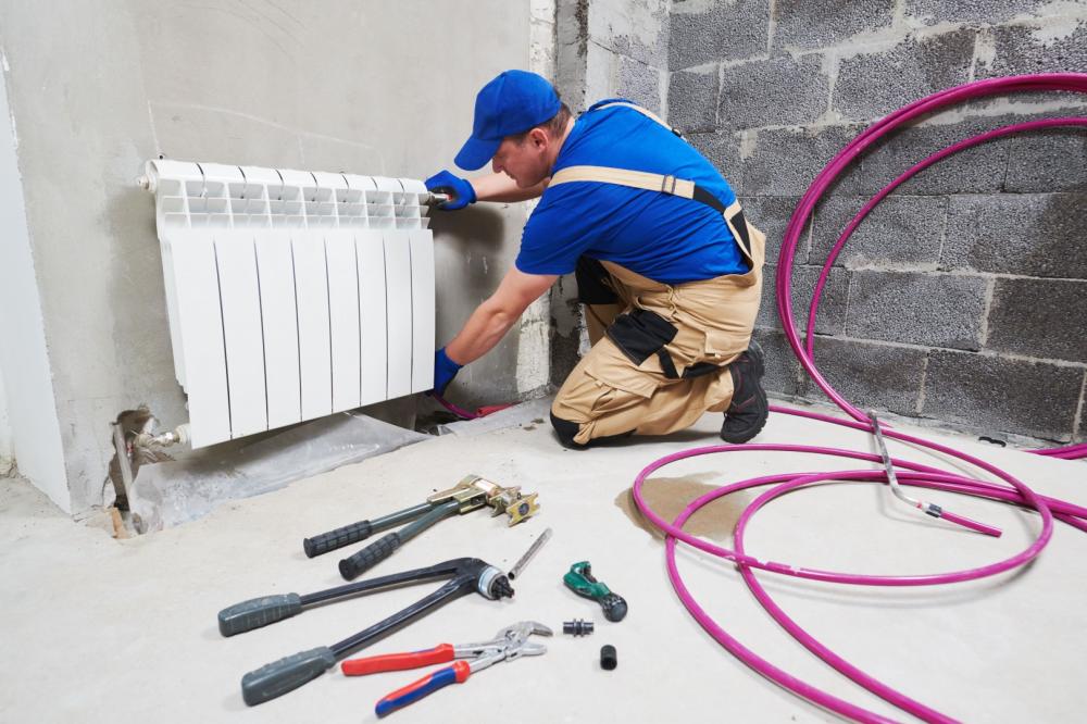 Plombier installant un radiateur mural